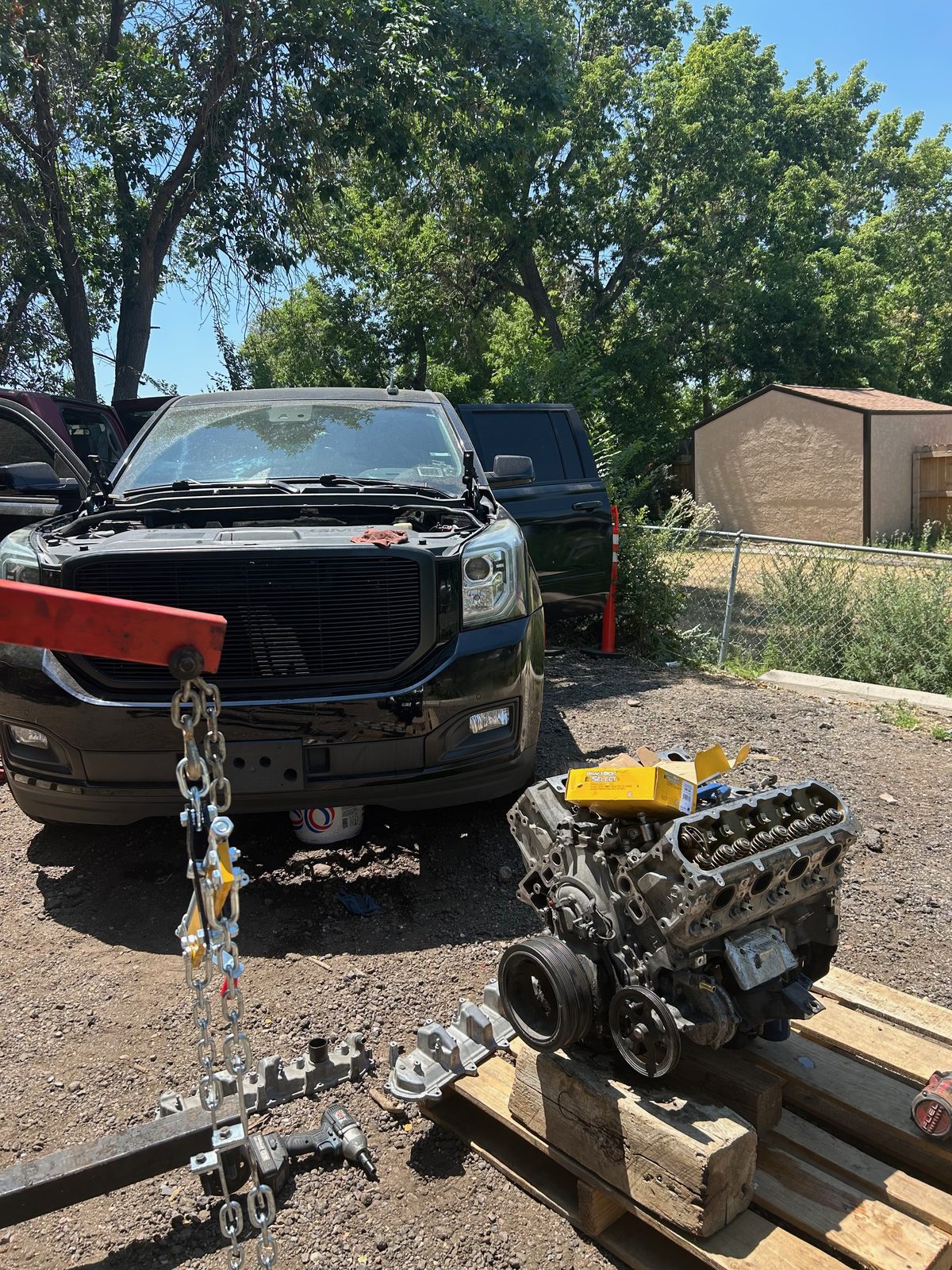V8 engine pulled and set on a pallet beside a black pickup during an on-site engine replacement